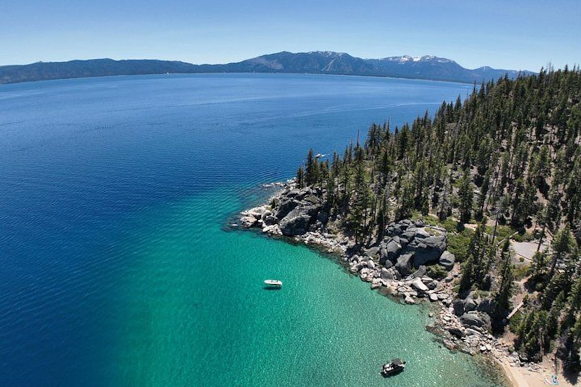 Un paisaje costero con un lago azul cristalino, una orilla rocosa y un bosque denso. 1