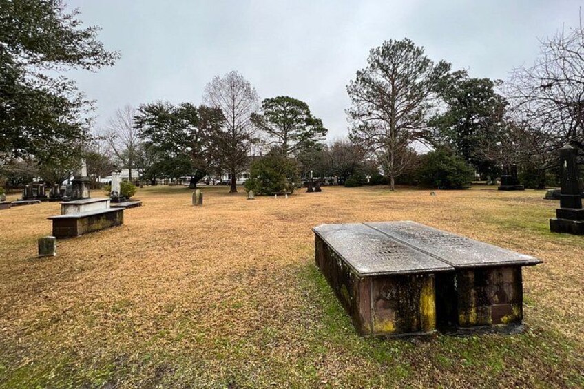 A cemetery with gravestones, a wooden bench, and leaf-covered ground. 5