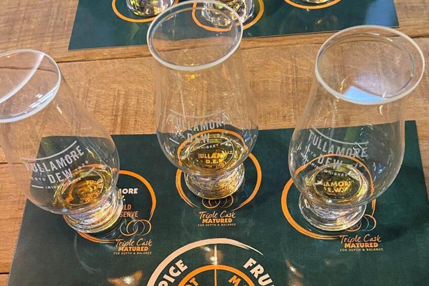 Three glasses of whiskey on a wooden table with a green placemat. 5