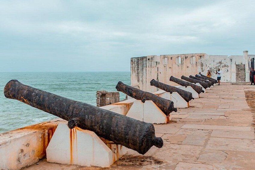 Een rij oude kanonnen langs een stenen muur aan de zee. 1