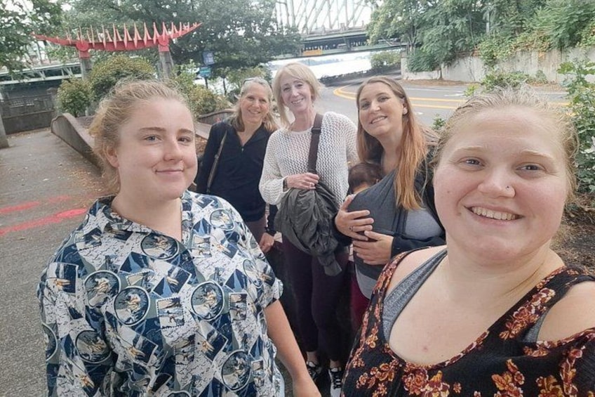 Un grupo de personas de pie al aire libre, con un puente y follaje en el fondo. 5