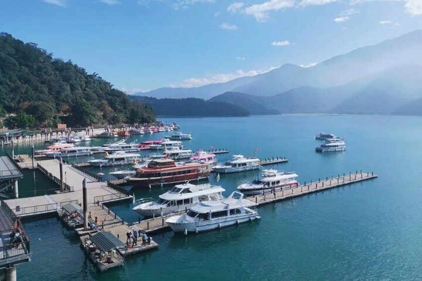 Ein Yachthafen mit vertäuten Booten, einer Pier und Bergen im Hintergrund. 1