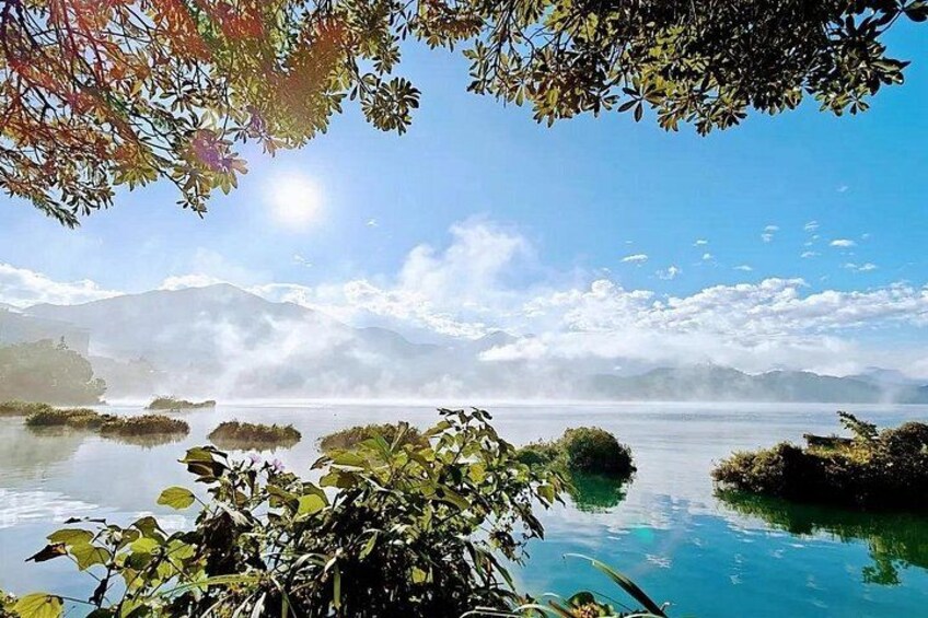 Un lago tranquilo con reflejos nítidos, rodeado de exuberante vegetación y montañas distantes. 5