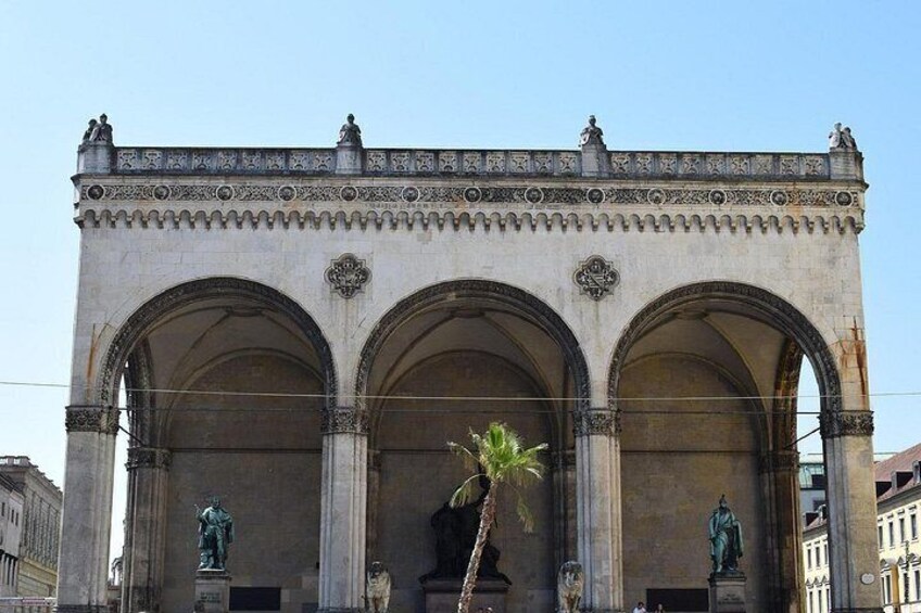 A historic building with three arches, statues, and intricate architectural details. 4