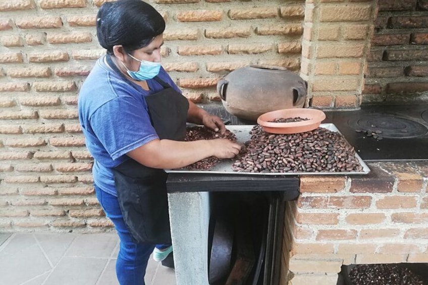 A person working with coffee beans on a table near a brick oven. 2