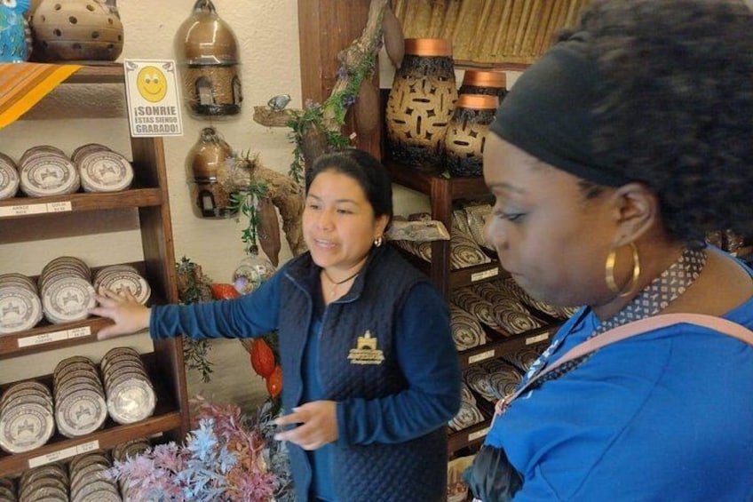 Una persona señala una estantería con objetos de cerámica en una tienda. 2
