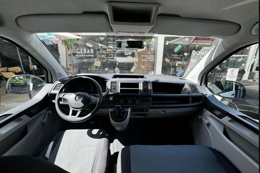 The interior of a car with a steering wheel, dashboard, and seats. 3