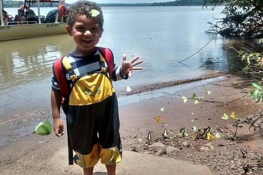 A child standing by a lake with a boat in the background. 4