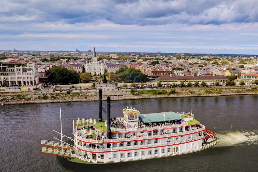 Ett ångfartyg som heter ”Clyde New Orleans” färdas på en flod, med en stadsbild i bakgrunden. 1
