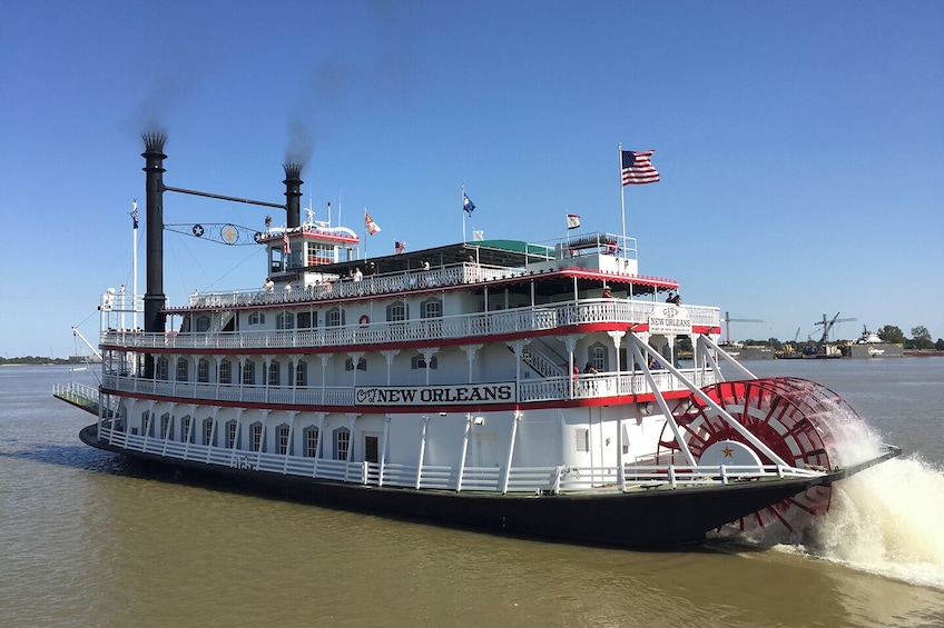 En ångbåt vid namn ”City of New Orleans” med ett stort ånghjul, flera däck och amerikanska flaggor. 3