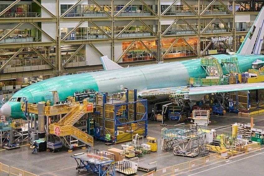 An airplane in a manufacturing facility with assembly lines and equipment. 1