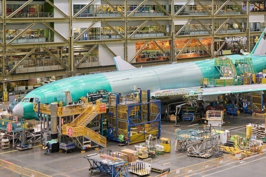 A large aircraft in an assembly area with various equipment and structures around it. 4