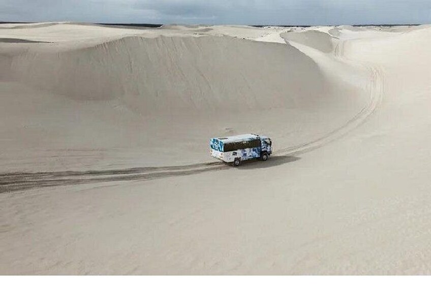 A bus driving on a sandy dune. 4