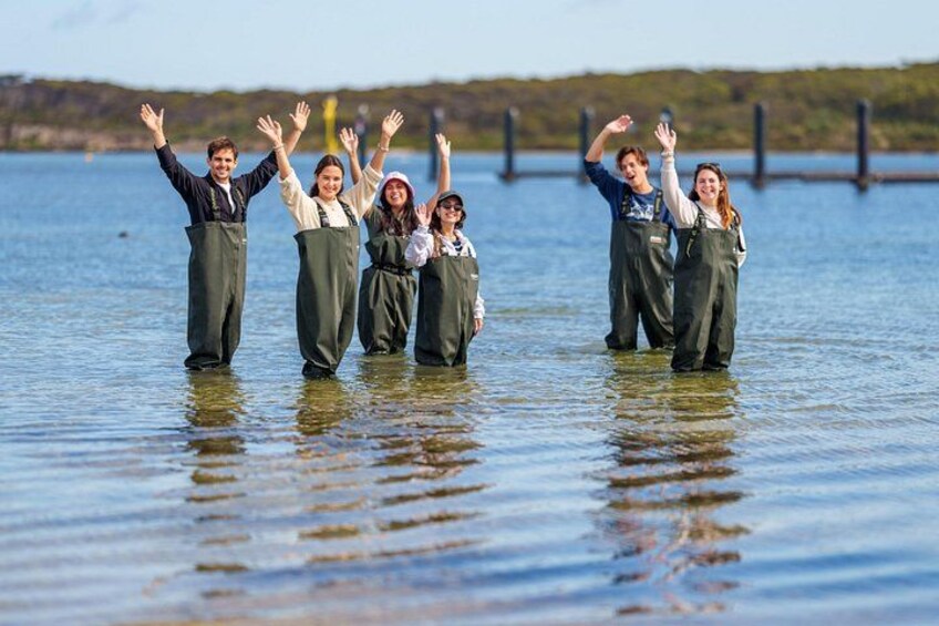 People in waders standing in water with their arms raised. 4