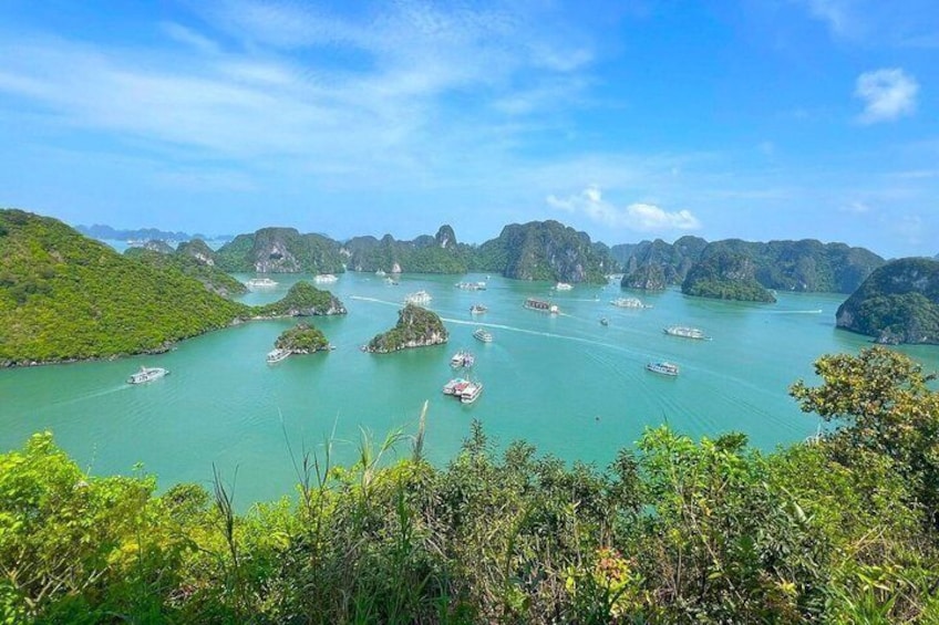 A coastal landscape with numerous boats on turquoise waters, surrounded by lush green hills and scattered islands. 5