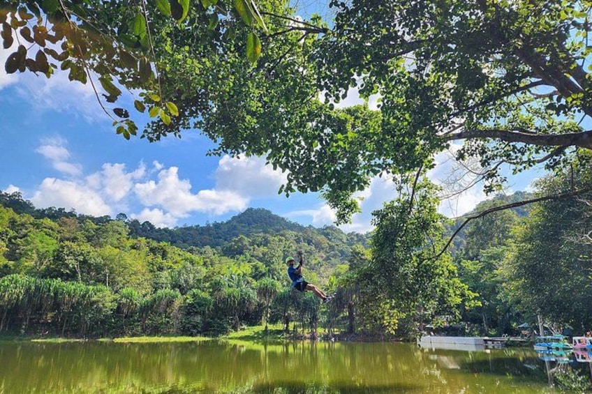 A person swinging on a swing over a lake surrounded by lush greenery and hills. 5