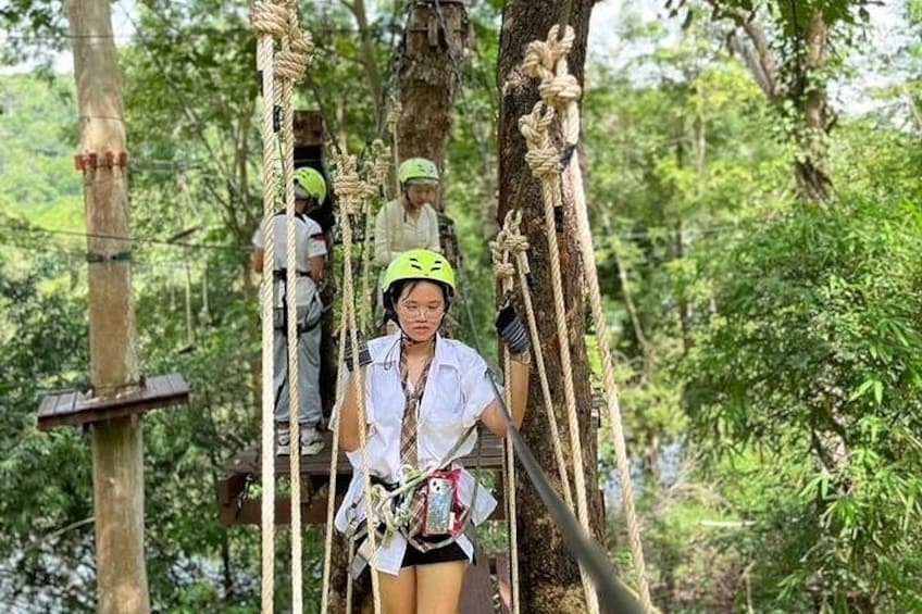 A person on a rope bridge in a forest. 2