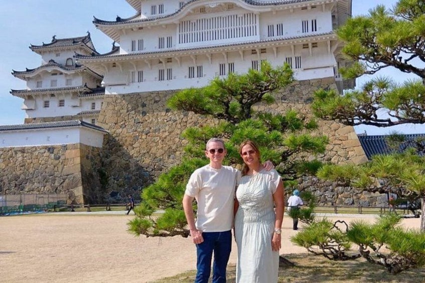 A castle with traditional architecture, a person in a white dress, and a pine tree. 1
