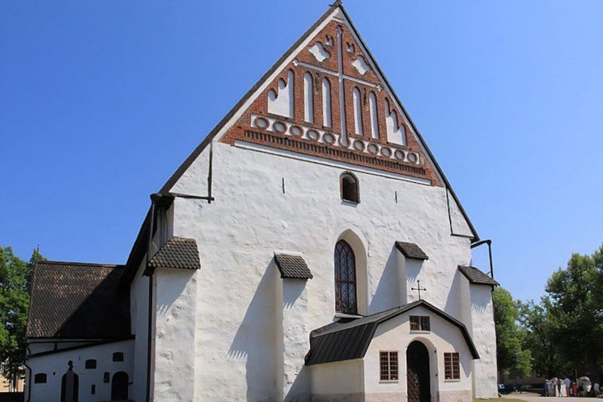 A white church with a red and white patterned roof, arched windows, and a bell tower. 2