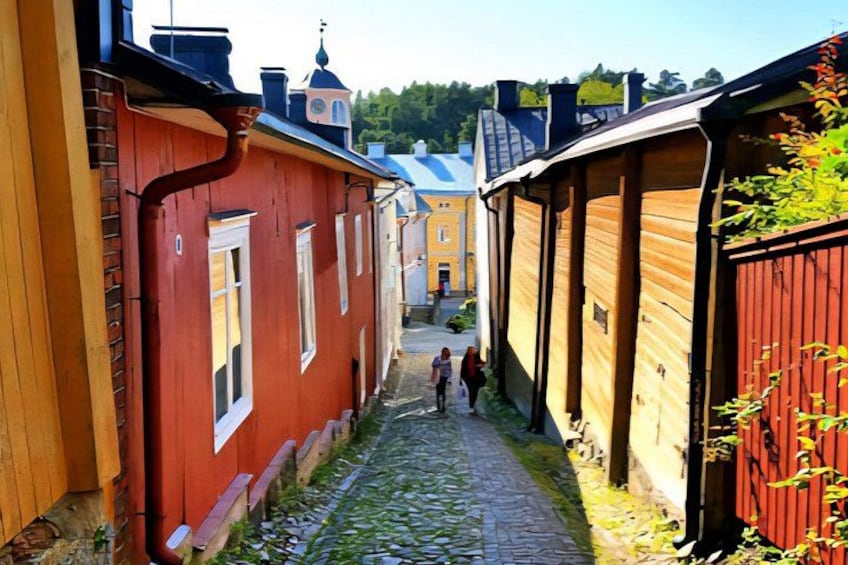 A narrow cobblestone street flanked by red and yellow buildings with a church in the background. 3