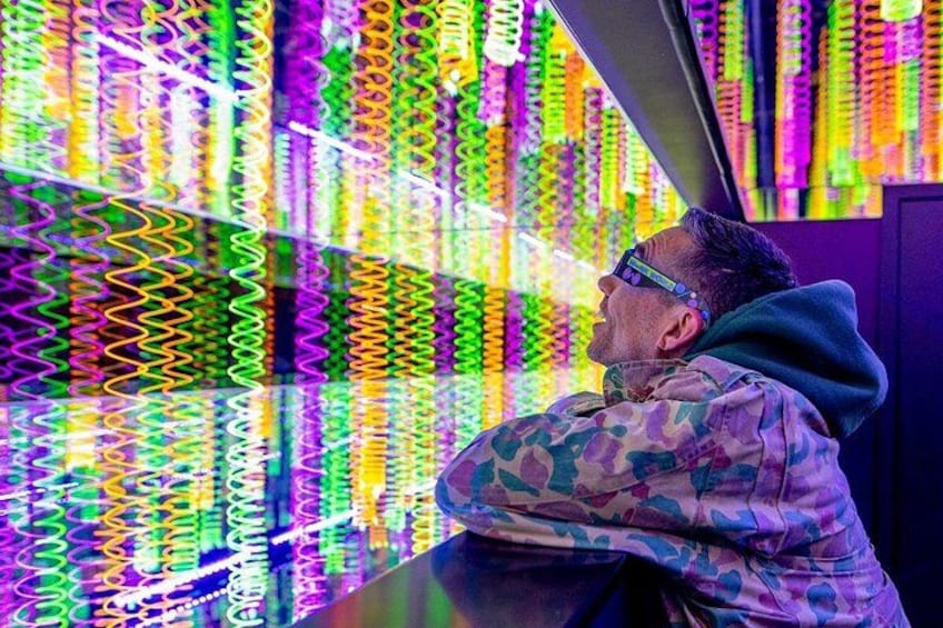 Une personne vêtue d’un uniforme de camouflage, observant des surfaces colorées et réfléchissantes. 1
