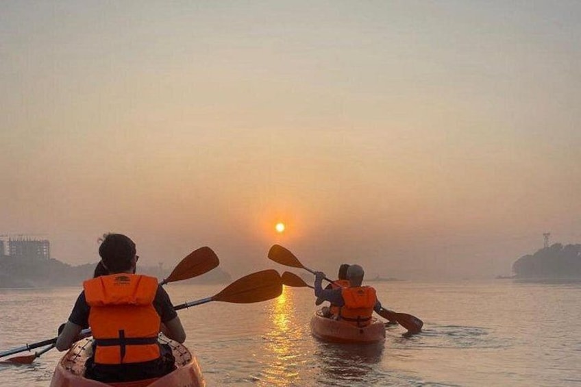 Dos personas en kayak sobre un agua tranquila al amanecer. 1