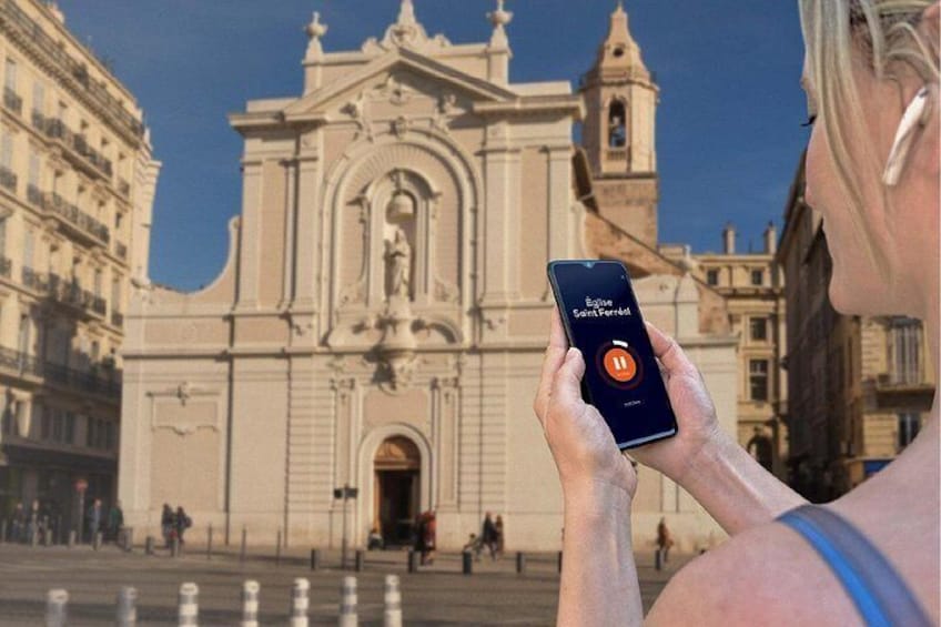 A person holding a smartphone with a map application, standing in front of a historic church with a bell tower. 5