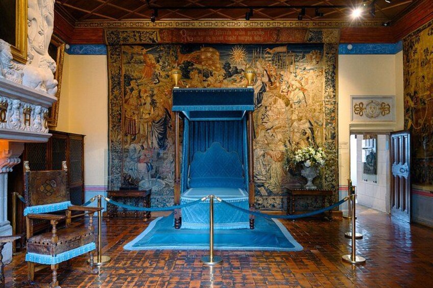 Una habitación con una alfombra azul grande, un sillón tipo trono y un tapiz con un dragón. 2