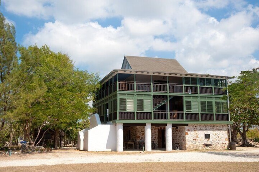 A two-story building with green railings and a stone base, surrounded by trees. 5