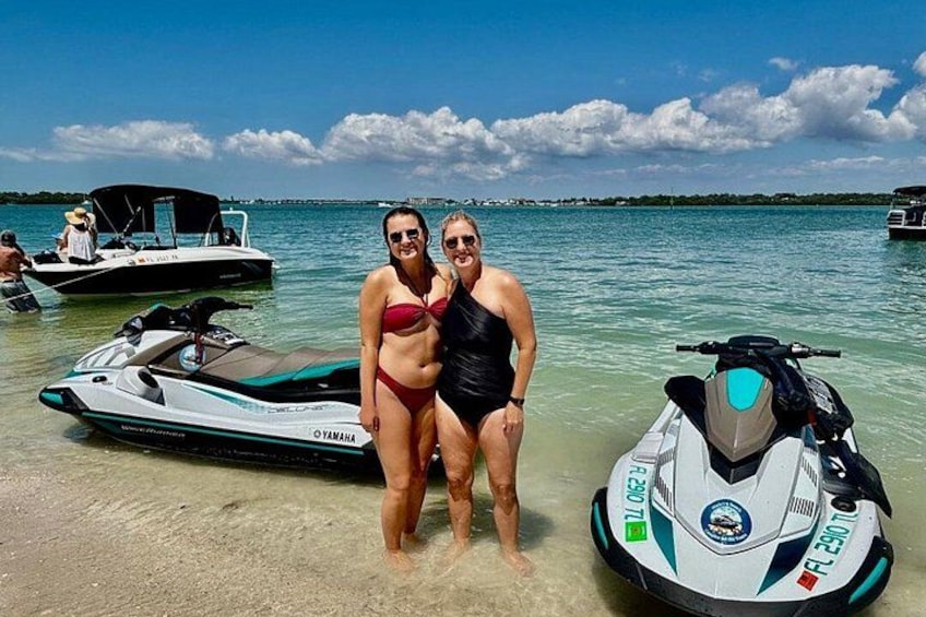 Due persone in piedi su una spiaggia, con jet ski sullo sfondo. 5