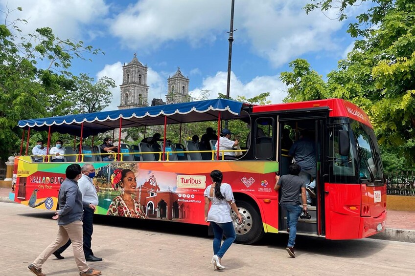 A red Turibus bus with passengers boarding and alighting. 5