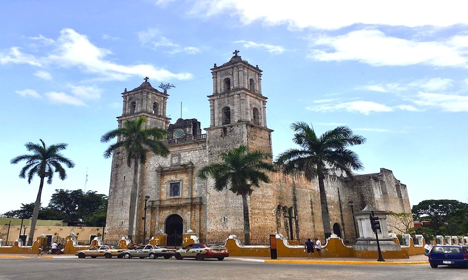 A historic church with two bell towers and palm trees in front. 1