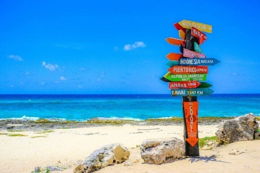 Une plage avec un panneau indiquant les distances vers différents pays. 5