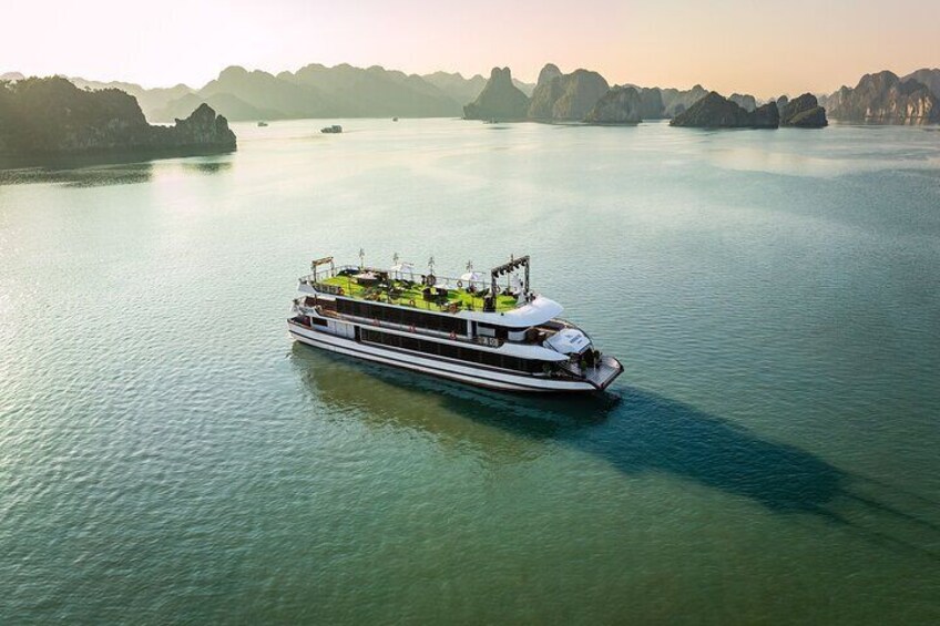 Un barco de crucero fluvial blanco con cubierta verde y varios niveles, navegando sobre aguas tranquilas con islas a lo lejos. 1