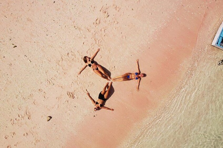 A beach with three people sunbathing. 3