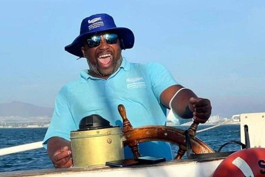 Een persoon aan het roer van een boot, met een stuurwiel en een reddingsboei. 2