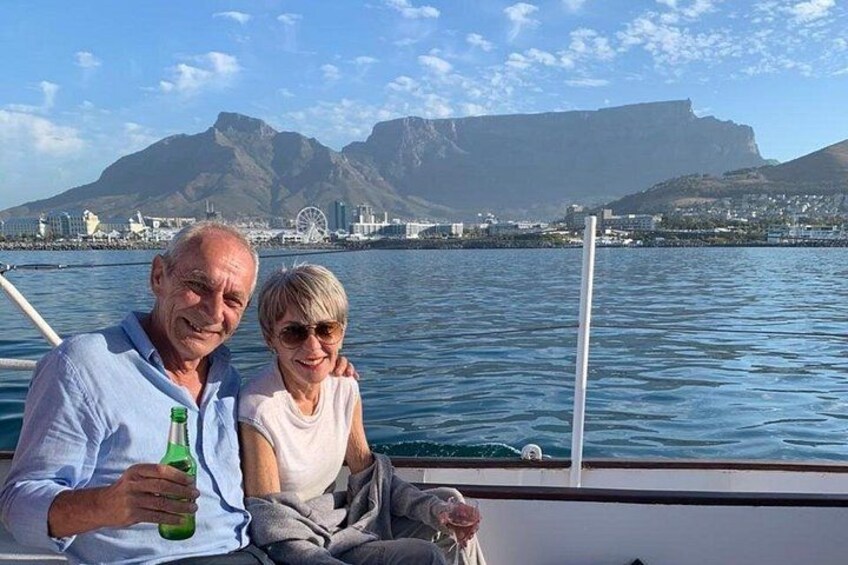 Een koppel op een boot, met een stadsgezicht en bergen op de achtergrond. 4