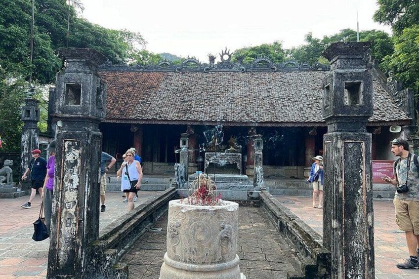 Un sitio histórico con pilares de piedra, techo de tejas y una fuente central. 4