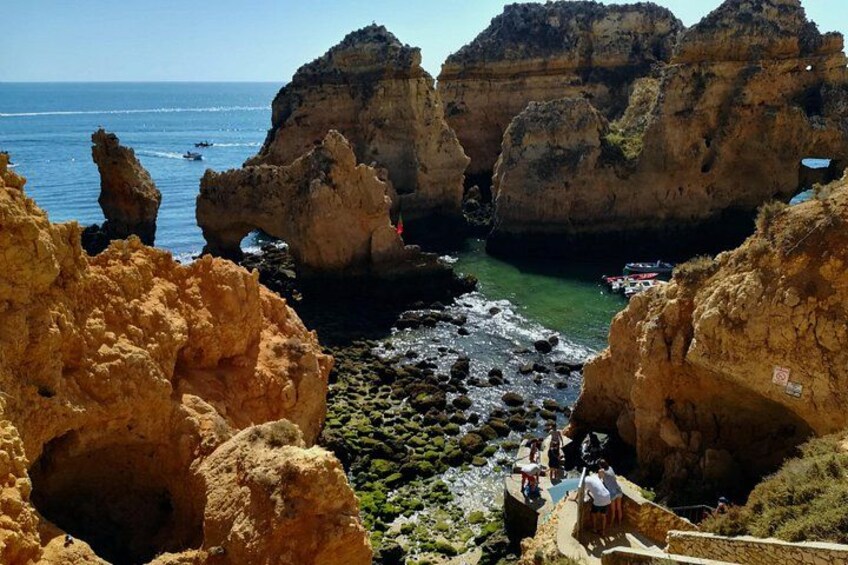 Un paisaje costero con acantilados rocosos, un canal estrecho y un pequeño barco a lo lejos. 5