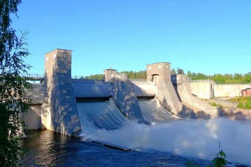A dam with water flowing over spillways, a bridge, and a clear sky. 3