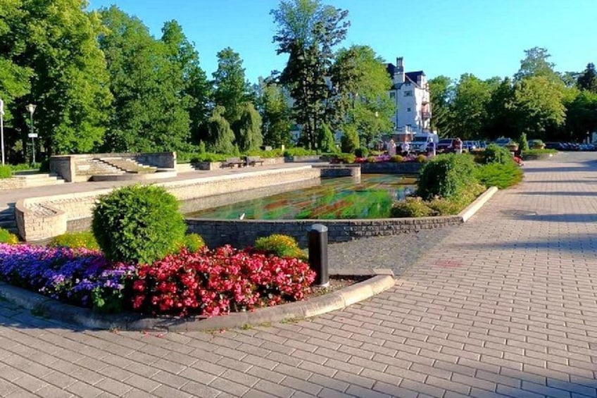 A paved walkway, a water feature with colorful flowers, and a building in the background. 4