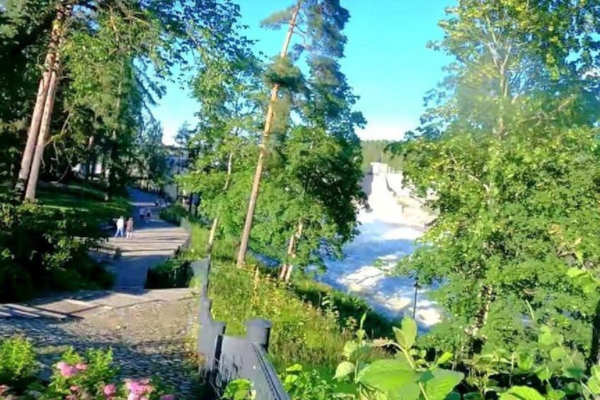 A pathway surrounded by lush greenery, a clear sky, and a distant waterfall. 5