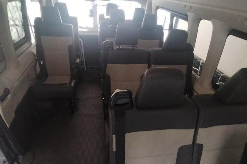 A vehicle interior with multiple rows of seats, a central aisle, and a rear view of the vehicle. 5