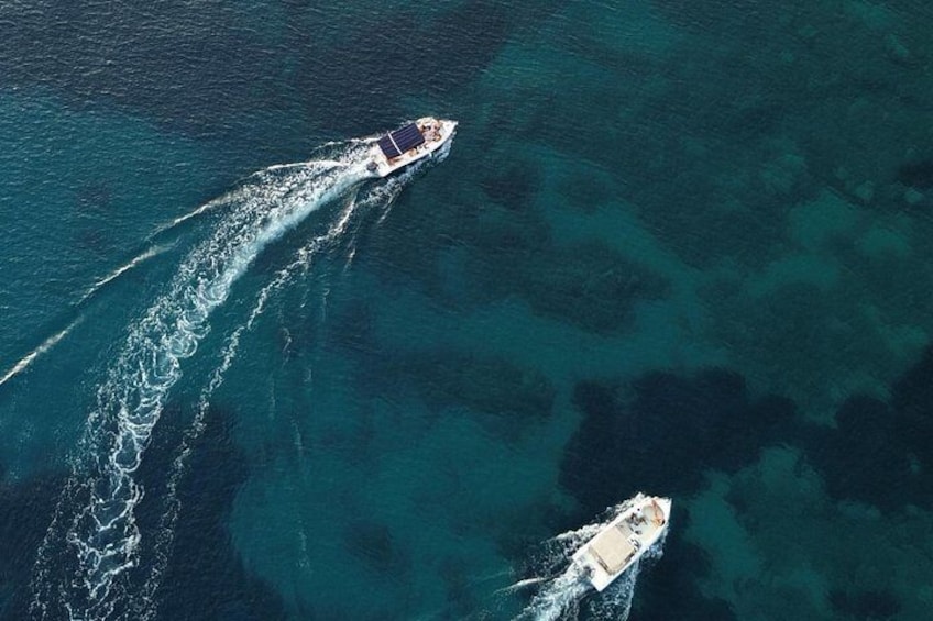 Two boats on a turquoise sea with one boat creating a wake. 5