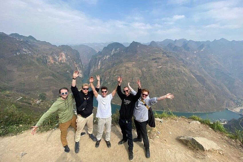 A group of people standing on a mountain ridge with a valley and lake in the background. 3