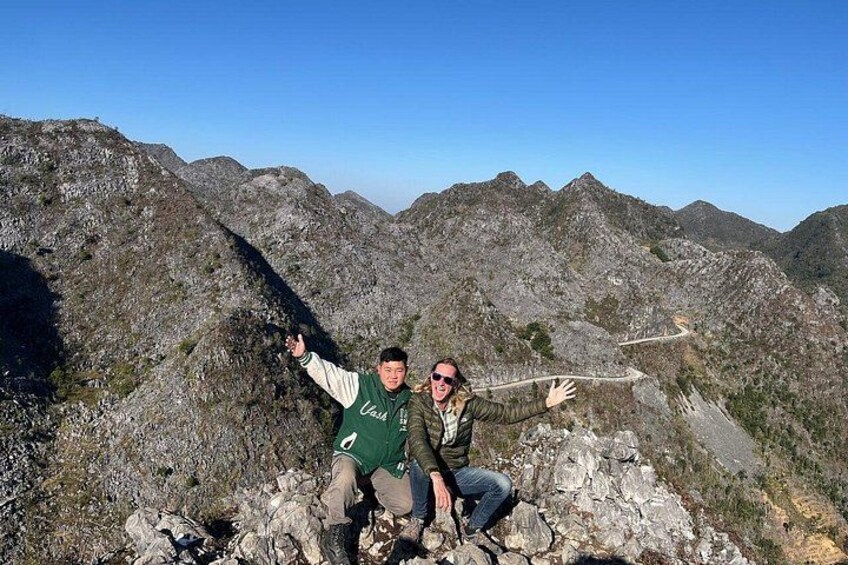 Two people on a rocky mountain with a winding road. 5