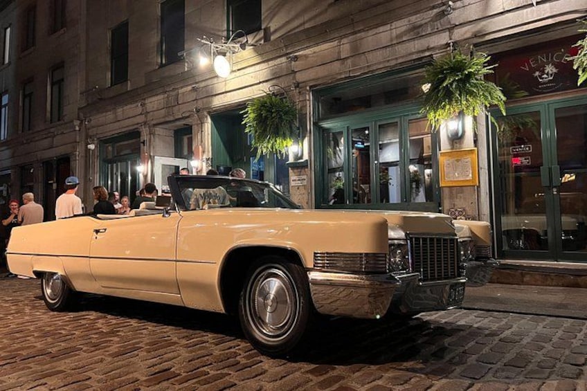 A vintage convertible car parked on a cobblestone street. 3