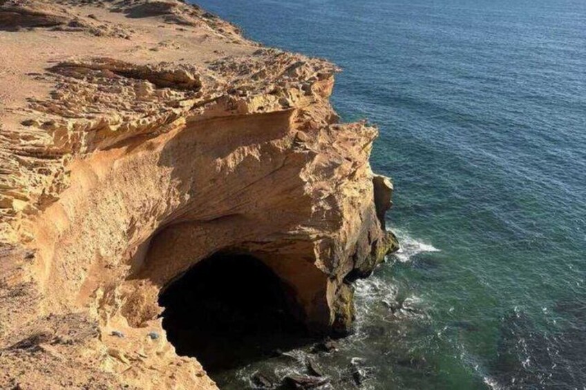 A coastal rock formation with a cave entrance. 3