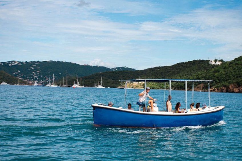 Un bote azul sobre aguas tranquilas con gente a bordo, rodeado de un paisaje montañoso y otros barcos a lo lejos. 3