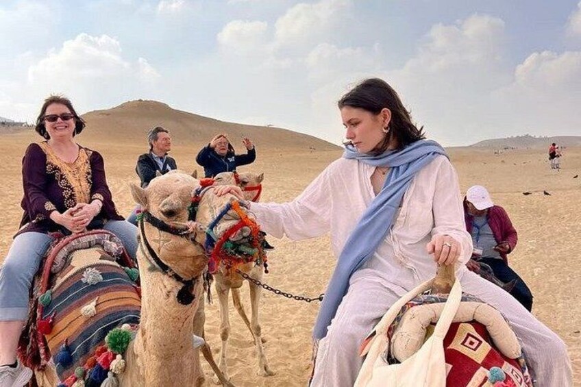 A desert landscape with people riding camels. 3
